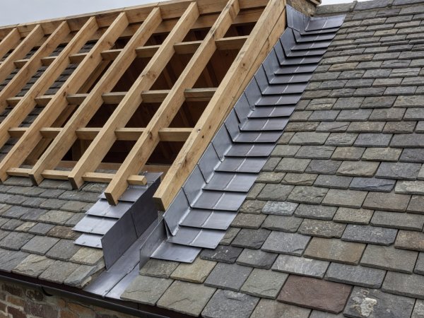 Soft-lit 3D architectural render showing stepped lead chimney flashings, oak rafters, and diminishing stone roof slates